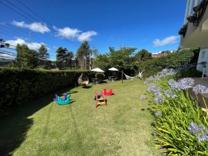 a yard with some chairs on the grass at Vila de Charme Suítes in Campos do Jordão