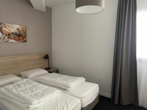 1 Schlafzimmer mit 2 Betten mit weißer Bettwäsche und einer Lampe in der Unterkunft Gourette, appart 3 pièces, 8 pers, animaux admis - FR-1-860-2 in Gourette