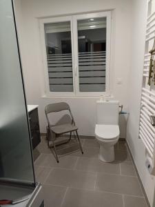 a bathroom with a toilet and a chair and a window at Gite Haute Epine "Ma Vie Là " Studio avec cuisine in Haute-Épine