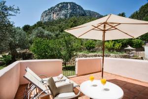 une terrasse avec une table, un parasol et des chaises dans l'établissement Hotel Rural S'Olivaret & Spa, à Alaró