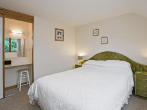 a bedroom with a large white bed with a green headboard at Grebe Cottage in Dilham