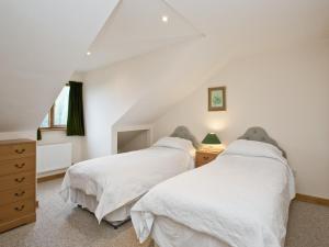 two beds in a bedroom with white walls at Grebe Cottage in Dilham