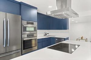 a kitchen with blue cabinets and stainless steel appliances at Bright Three-Bedroom Modern Apartment with Private Balcony in Hollywood Beach