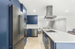 a kitchen with blue cabinets and a stainless steel refrigerator at Bright Three-Bedroom Modern Apartment with Private Balcony in Hollywood Beach