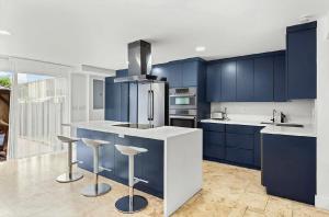 a kitchen with blue cabinets and bar stools at Bright Three-Bedroom Modern Apartment with Private Balcony in Hollywood Beach