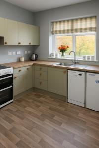 cocina con armarios blancos y suelo de madera en The Holm, en Canonbie