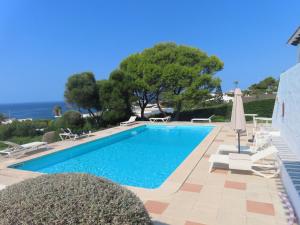 een zwembad met stoelen en een parasol en de oceaan bij Binibeca Panorama incredibile in Sant Lluis +28 foto's