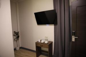 a room with a tv on the wall and a table at Locale District Boutique Hotel in Quezon