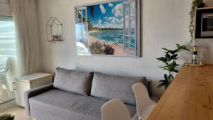 ein Wohnzimmer mit einem Sofa und einem Bild von einem Strand in der Unterkunft Balcon al mar in Bellreguart