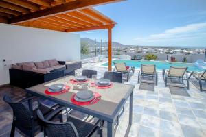 Un patio con mesa y sillas y una piscina. en 3 bedroom villa with pool and jacuzzi, en Playa Blanca