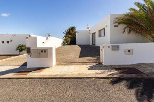 una casa con edificios blancos y palmeras en 3 bedroom villa with pool and jacuzzi, en Playa Blanca