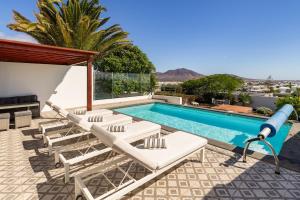 Una piscina con tumbonas junto a una piscina. en 3 bedroom villa with pool and jacuzzi, en Playa Blanca