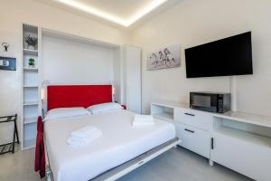 a white bedroom with a bed and a flat screen tv at Harmony's Nest - Vicino a treno e Fiera Milano in Rho