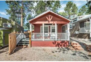 伍德兰帕克Tiny House Get Away的一栋粉红色的小房子，带门廊和栅栏。