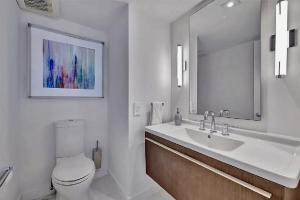 a bathroom with a sink and a toilet and a mirror at Luxurious Three-Bedroom Oceanfront Apartment with Private Balcony in Hollywood Beach +47 photos