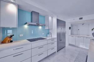 a large kitchen with white cabinets and blue walls at Luxurious Three-Bedroom Oceanfront Apartment with Private Balcony in Hollywood Beach
