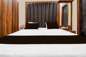 a bedroom with a large white bed with black pillows at Hotel O The Kesar Inn in Lucknow