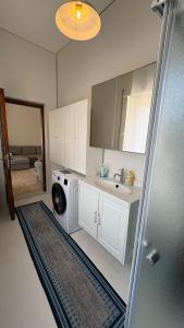 une salle de bains avec lave-linge et lavabo dans l'établissement Villa Pietra Sardinia - Luxury 165 m2 Historic Stone House with Fireplace and Rooftop, à Tempio Pausania