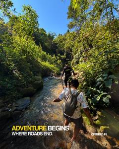 two people walking across a river in a forest at Offbeat Jn in Sukhia Pokhari +4 photos