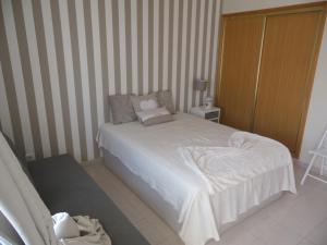 Dormitorio pequeño con cama blanca y paredes a rayas en Moura 11, en Vilamoura