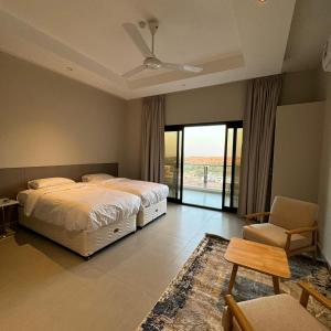 a bedroom with a bed and a chair and a window at Dune View Luxury Villas in Ḩawīyah