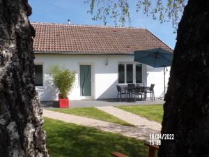 ein weißes Haus mit einem Tisch und einem Regenschirm in der Unterkunft Maison ROSAE Betula 
