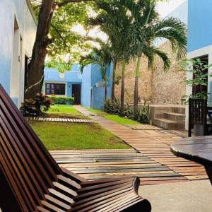 a wooden bench sitting on a patio with palm trees at Hotel Maculís in Campeche