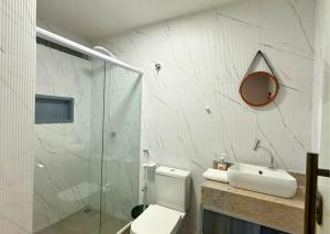 a bathroom with a shower and a toilet and a sink at Luxo Frente Mar em 7 Qtos com Ar sendo 4 suites para até 18 pessoas, 2 Jacuzzi Aquecidas, piscina, brinquedoteca, 5min de Castelhanos in Anchieta