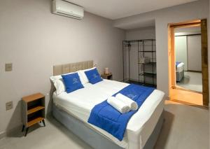 a bedroom with a large bed with blue and white pillows at Luxo Frente Mar em 7 Qtos com Ar sendo 4 suites para até 18 pessoas, 2 Jacuzzi Aquecidas, piscina, brinquedoteca, 5min de Castelhanos in Anchieta