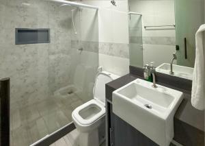 a bathroom with a sink and a toilet and a shower at Luxo Frente Mar em 7 Qtos com Ar sendo 4 suites para até 18 pessoas, 2 Jacuzzi Aquecidas, piscina, brinquedoteca, 5min de Castelhanos in Anchieta