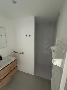a white bathroom with a sink and a mirror at Bleu horizon in Rosnoën
