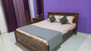 a bedroom with a large bed with purple walls at Moonlit resort in Minuwangoda