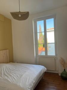 een slaapkamer met een bed en een groot raam bij Location Ile d'Oléron, plage et commerces à pieds in Le Château-dʼOléron