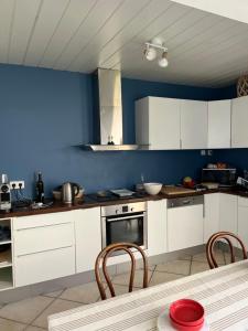 een keuken met witte kasten en een blauwe muur bij Location Ile d'Oléron, plage et commerces à pieds in Le Château-dʼOléron