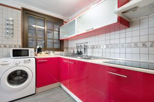 eine Küche mit roten Schränken und einer Waschmaschine in der Unterkunft Casita Independiente Frente al Mar in El Pris