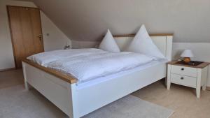 a white bed with white sheets and pillows on it at Ferienhaus Hummel-Nest in Laußnitz