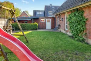 een achtertuin met een glijbaan en een huis bij Elkjer 24 in Großenwiehe