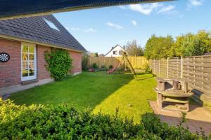 een achtertuin met een speeltuin en een schommel bij Elkjer 24 in Großenwiehe