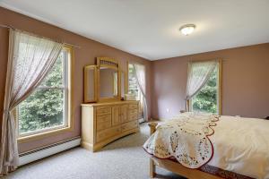 a bedroom with a bed and a dresser and two windows at Four Seasons Chalet in Waterbury Center