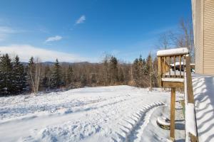 a yard covered in snow with a wooden bench at Four Seasons Chalet in Waterbury Center