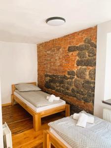 twee bedden in een kamer met een bakstenen muur bij Skansen- Bożejów in Radomierowice