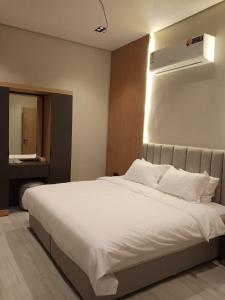 a bedroom with a large white bed and a air conditioner at اجواء الريف لبيوت العطلات in Dammam
