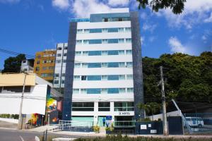a tall white building on the side of a street at Aquarena Hotel in Salvador