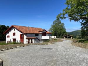 una casa blanca con techo rojo en una carretera en Le gite d'etxerria, en Arhansus