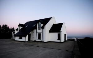 ein weißes Haus mit schwarzem Dach in der Unterkunft On the Rocks B&B in Greencastle
