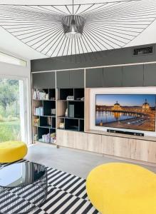 a living room with a tv and a yellow table at Villa d'Exception avec piscine & spa à Mérignac - Aeroport - Tram direct centre - Aéroparc Business Center Mérignac - Airbus Thales Safran - Hôpital Charles Perrens - Hôpital Pellegrin - ZI Espace Mérignac Phare in Mérignac +29 photos