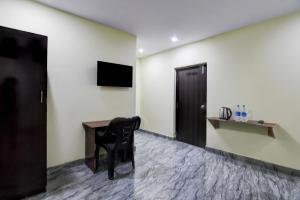 a room with a chair and a desk and a television at Hotel O Starlight B in Rushikonda