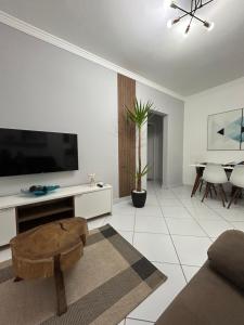 - un salon blanc avec une télévision et une table dans l'établissement Apartamento em Santos no Gonzaga em frente a praia, à Santos