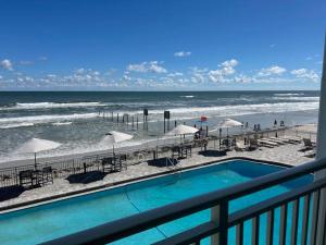 a swimming pool with chairs and umbrellas on the beach at Daytona Inn in Daytona Beach