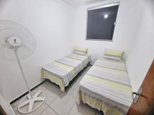 a small room with two beds and a fan at TH Flats GV in Governador Valadares +11 photos